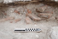 Brick pavers in an excavation unit with a marker to show size