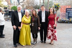 Two men and three women in formal attire standing in a row, smiling at an event