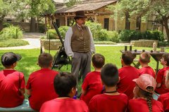 Students on an Alamo field trip listen to a living history demonstration.