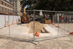 Fenced construction area on Alamo grounds with tourist in the background and a pedestrian only sign