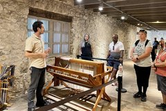 A man next to a weaving loom with a group in the Alamo Long Barrack