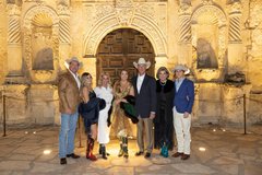 A group of men and women standing in front of Alamo Church