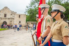 Three marines standing at attention to the side outside of Alamo Church