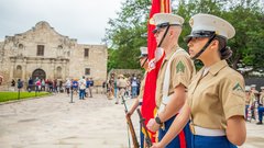 Three marines standing at attention to the side outside of Alamo Church