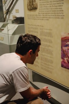 A man reads an interpretation panel inside the Alamo Exhibit