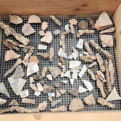 Nail, brick, and glass artifacts on a netted background