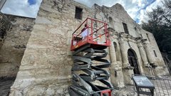 Alamo Conservator on an electric scissor lift on the plaza-facing part of the Church