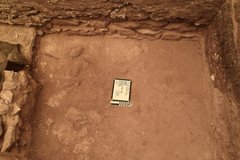 Whiteboard and ruler on dirt center in an excavation unit