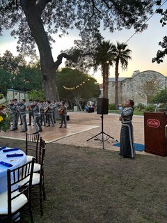 Mariachi singer performing next to a podium with the band in the background