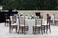 Table set up with a white floral centerpiece and white linen on an outdoor patio
