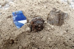 Ceramic piece, glass, and loop shank button on a bed of dirt