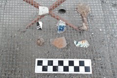 Artifacts recovered from an excavation unit on a wire surface with a ruler to show size