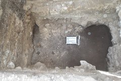 Inside of a rocky excavation unit with a path to a deeper opening