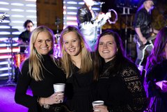 Three smiling women in front of concert stage in Alamo Gardens