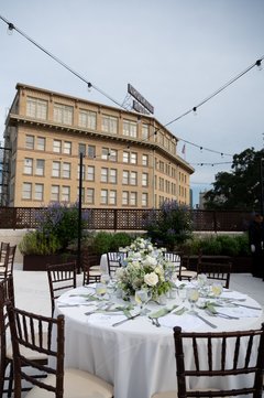 Table set out with white floral centerpiece and white linen, Crockett Hotel in the background