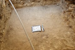 Square excavation area with a white board and ruler in the center