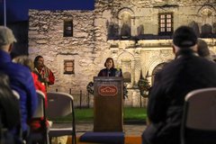 Speaker at a podium in front of Alamo Church