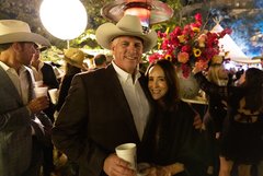 Man and woman in front of large pink and yellow floral arrangement in Alamo Gardens