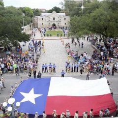 Large Texas flag being carried in front of the Alamo in a parade