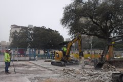 Construction truck and workers in dirt area to the left of Alamo Church