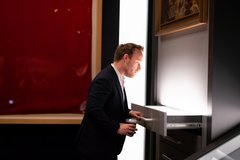 Man looking at artifacts inside an open drawer in a gallery