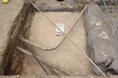 Inside of excavation unit with curved piping and a rolled up tarp to the side