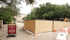 Fenced construction area on Alamo grounds with tourist in the background and a pedestrian only sign