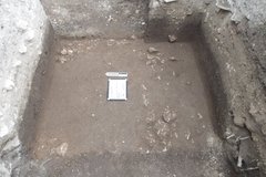White board and marker on dirt surface inside an excavation unit