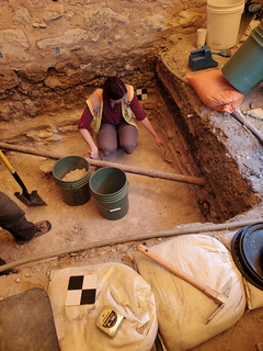 Archaeologists working on removal of the compacted surface in excavation unit