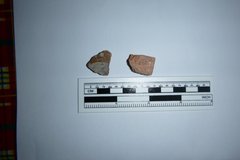 Two small ceramic sherds next to a ruler to show size