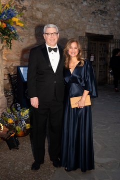 Man in a black tuxedo and woman in a navy blue gown outside of Alamo Church