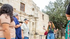 Tour guide speaking to a group of visitors in front of Alamo Church