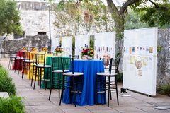 Cocktail tables with colorful linens line the Alamo Wall of History