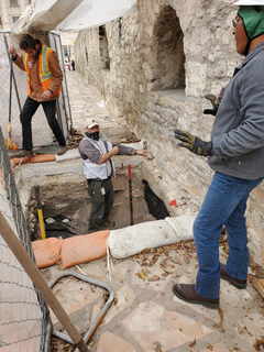 Archaeologists tamping soils down during backfilling in excavation unit