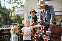 Living historians showing a cannon to two young girls