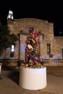 Tall floral arrangement set on white round table outside of Alamo Gift Shop