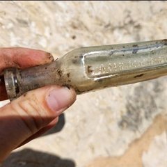 Two fingers holding a small glass bottle