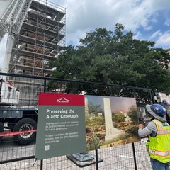 Sign on fence wrap surrounding construction around Alamo Cenotaph