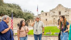 Tour guide speaking to visitors in front of Alamo Church