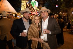 Three guests in Alamo Gardens in front of lighted installation of Juan Seguin on horseback