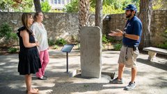 Two women listening to an Alamo History Interpreter next to the Japanese Monument