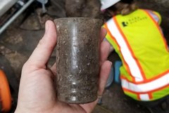 Hand holding what appears to be a drinking glass found in an excavation site