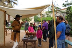 Living History volunteer demonstrating daily use items from the 1830s to a group