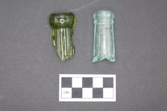 Two historic glass bottle finishes on a gray background next to a ruler for size