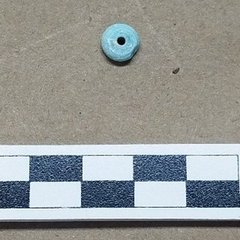Light green round glass with a hole in the middle found in excavation
