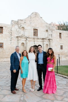 Five people standing, smiling in front of Alamo Church