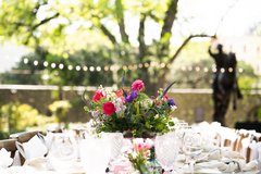Centerpiece with pink, purple, and white flowers on a set table