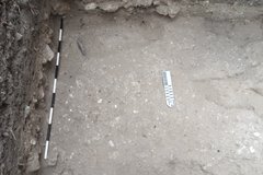 Marker and pipe on a flat lime surface inside an excavation unit