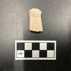 Red painted valero sherd next to a ruler for size