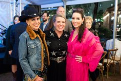 Three women in a row in western attire at an event
